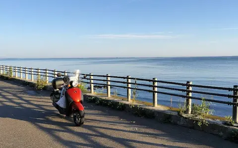 広大なサロマ湖と道路路肩に停めた原付の風景。