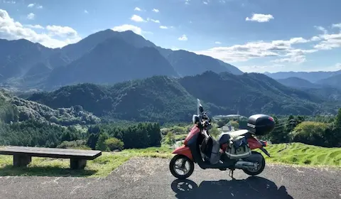 丸山千枚田と山々の景色を背景に移るバイク