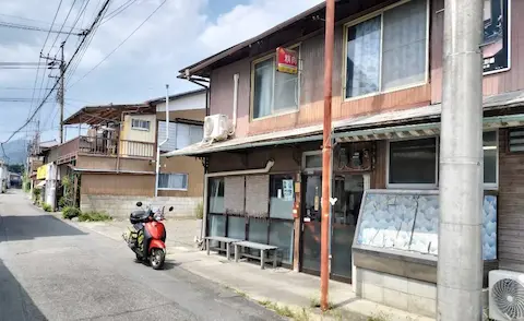 安田屋本店の外観。路地に店をかまえ、原付と一緒に映っている。