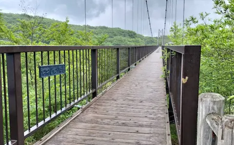 那須高原のつつじ吊橋。山々に囲まれたところに、長い吊橋が延びている。