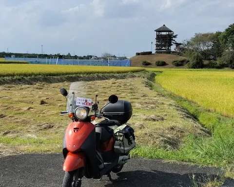 奥州アテルイの里田んぼアートの外観と原付スクーター。田んぼの中に展望台が立つ。