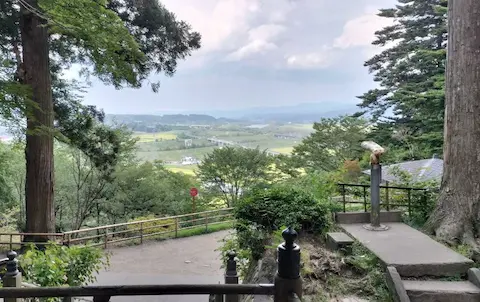 中尊寺からの景色。木々の間から見晴らしの良い景色が見える。