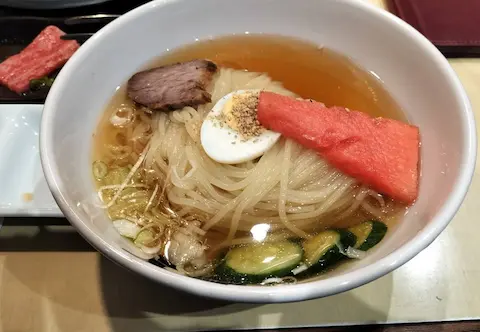 焼肉・冷麺 髭の盛岡冷麺。麺の上に、チャーシューやスイカ、キュウリが乗っている。