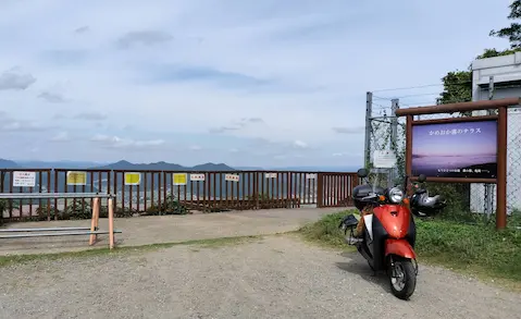 かめおか霧のテラスの看板と全景。原付と一緒に映っている。