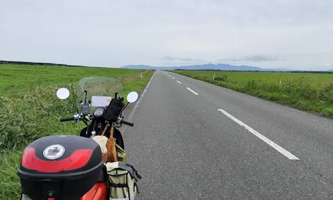 北海道の猿払エヌサカ線。草原に囲まれた真っすぐの道路と原付。