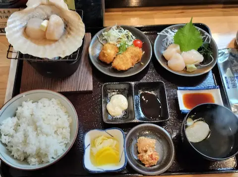 紋別の寿司処みらくのホタテ御膳。焼き、フライ、刺身、三升漬けのホタテと、ご飯類のセットが並ぶ。