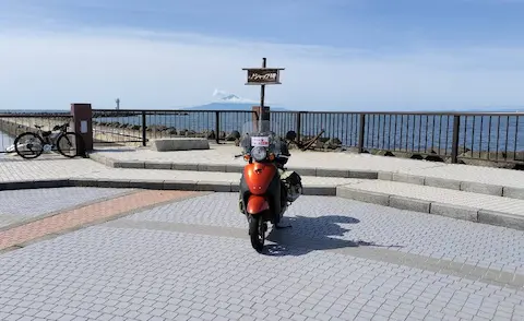 ノシャップ岬の看板と原付トゥデイ。背景に大海原が広がる。