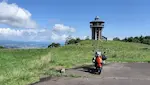 北海道の八雲育成牧場展望台とバイクの写真。タワー上の展望台と広がる山の景色。