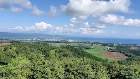 八雲育成牧場展望台からの景色。噴火湾の湾曲した海岸線と、山々の景色が見える。
