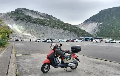 硫黄山駐車場からの景色。岩々の山と原付。