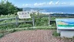 毛無山展望台の全景。眺望を説明した看板と、毛無山展望所と書かれた木の看板がある展望台から、小樽の街並みと海が見える。