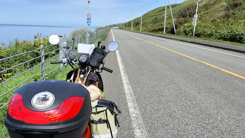 宗谷岬付近のオロロンライン。左手に海が広がり、バイクと直線道路が延びている。