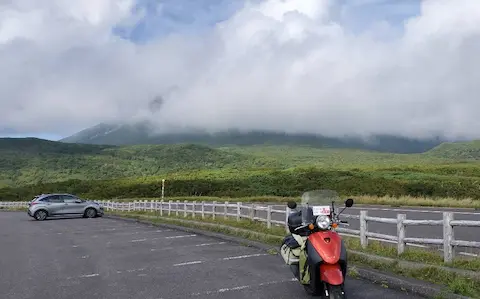 知床峠展望台駐車場とオレンジ原付のトゥデイ。羅臼岳が雲に隠れている。